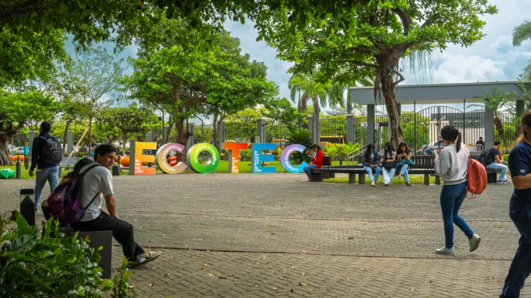 Estudiantes caminan junto al letrero de ECOTEC en el campus