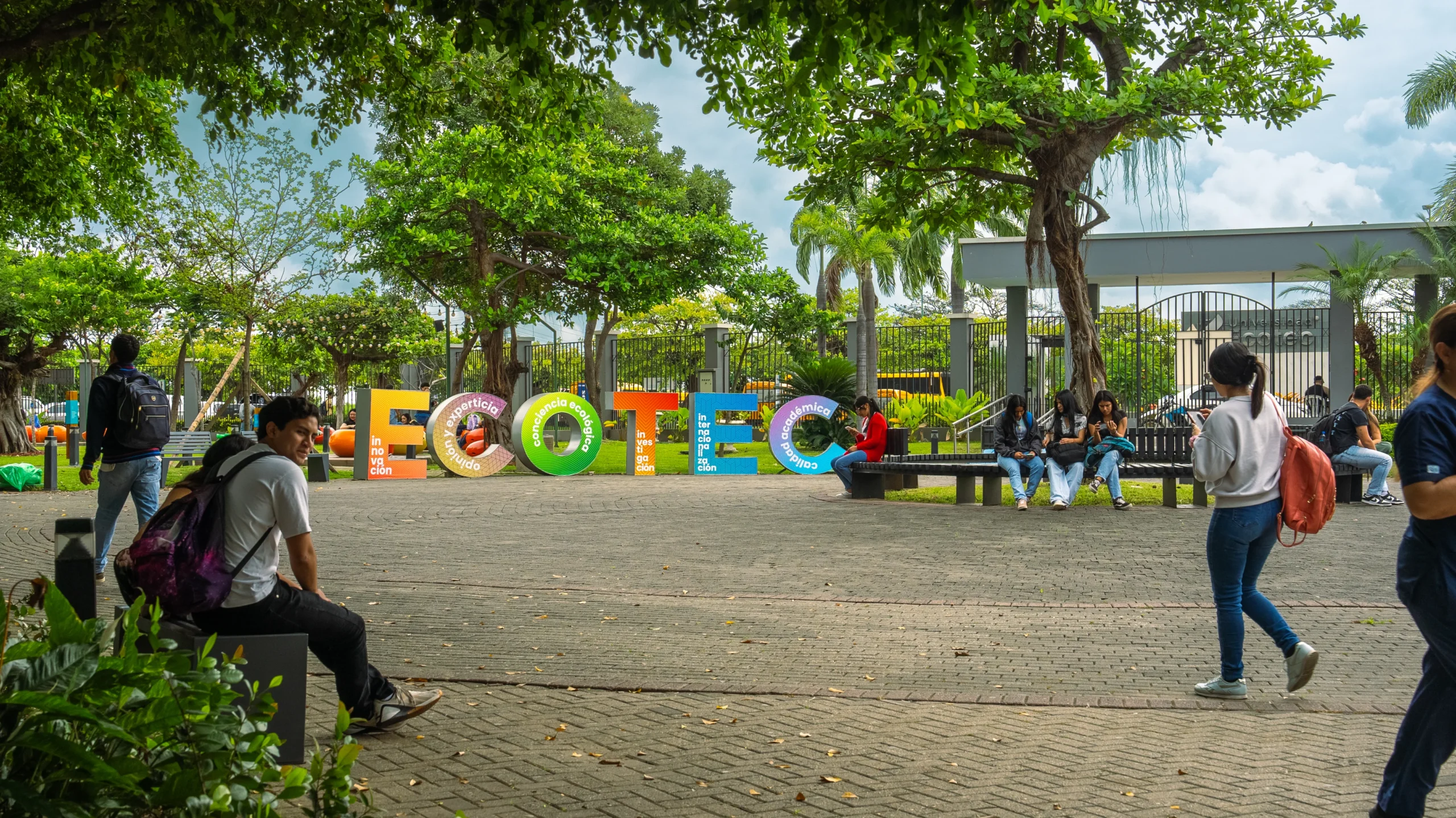 Estudiantes caminan por el campus junto al letrero colorido de ECOTEC