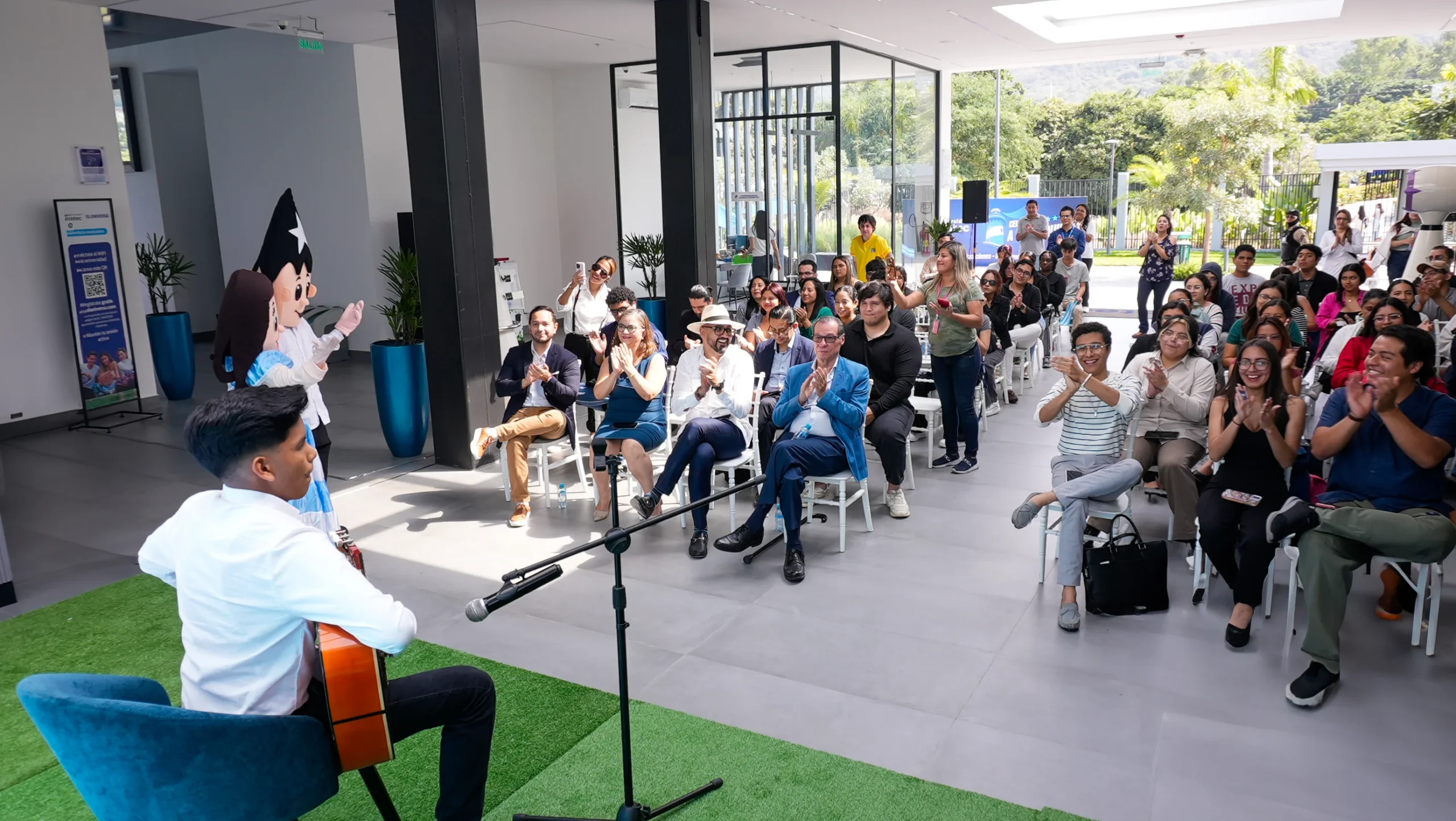 Músico toca la guitarra ante estudiantes en un evento del campus ECOTEC