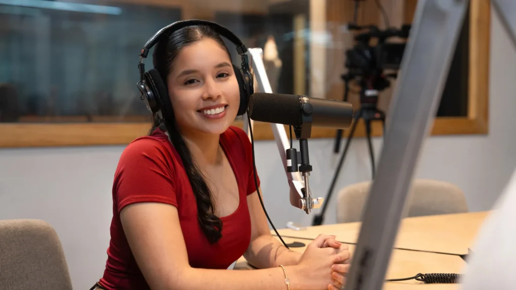 Estudiante de Comunicación sonríe frente al micrófono en una cabina de radio