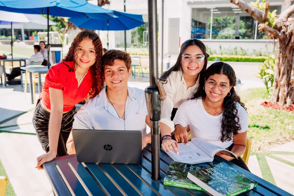 Estudiantes de ECOTEC estudian juntos en una mesa al aire libre del campus
